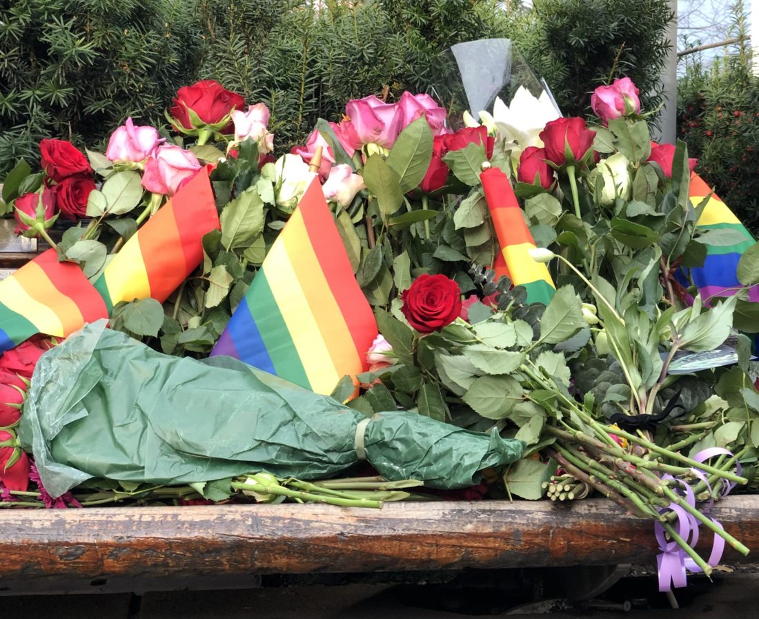 Benk med blomster og regnbueflagg