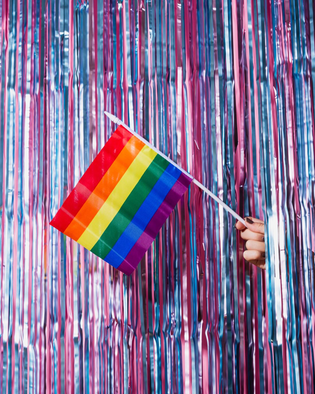 Regnbueflagg stikker ut gjennom en glittervegg i bi-flagg-fargene